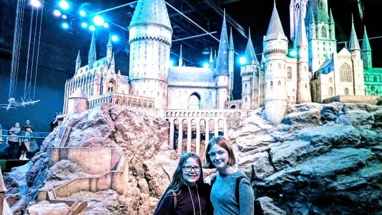 2 teens in London at harry Potter studios standing in front of a model of Hogwarts