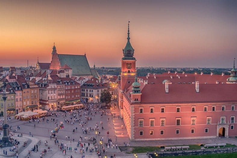 Dusk in Warsaw old town with tourists walking around near the castle. The Old Town should be one of the places to visit on your 2 days in Warsaw itinerary