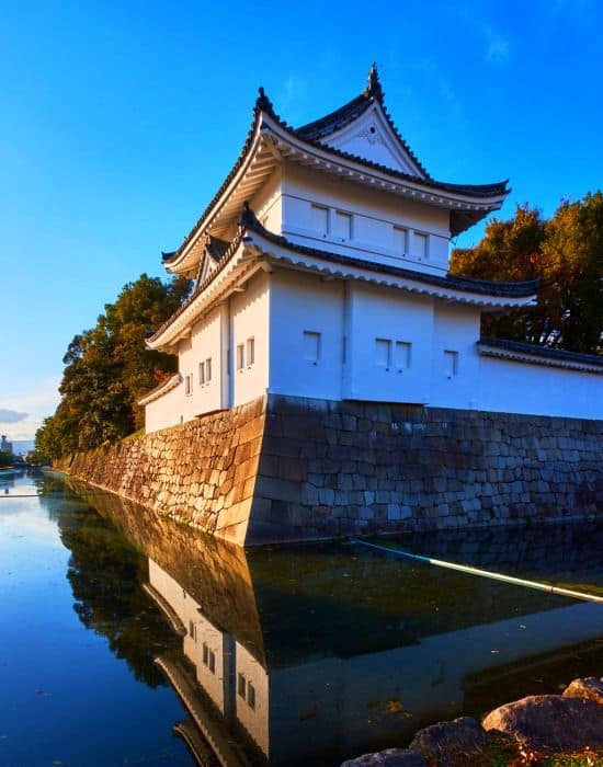 Old white castle sitting on the water's edge in Kyoto, Japan