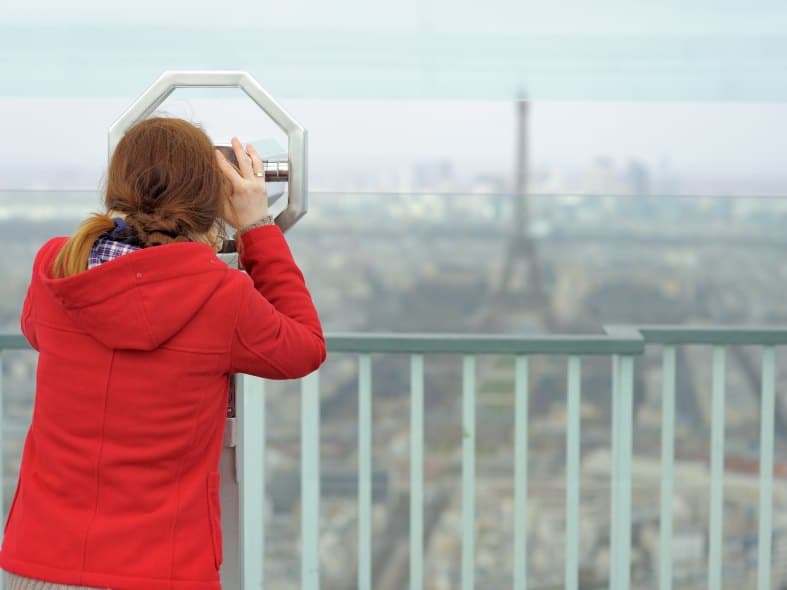 a teenage girl looking at the Eiffel Tower from tour montparnasse